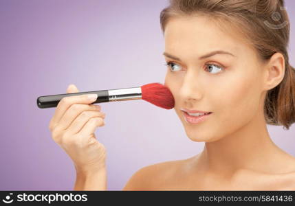 people, beauty, makeup and accessories concept - close up of young happy woman applying blush with brush over violet background