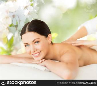 people, beauty, spa and body care concept - happy beautiful woman having back massage over green natural cherry blossom background