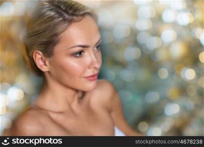 people, beauty, spa and relaxation concept - close up of beautiful young woman in swimsuit at swimming pool over holidays lights background