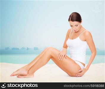 people, beauty, spa and resort concept - beautiful woman in cotton underwear touching her hips over infinity edge pool background