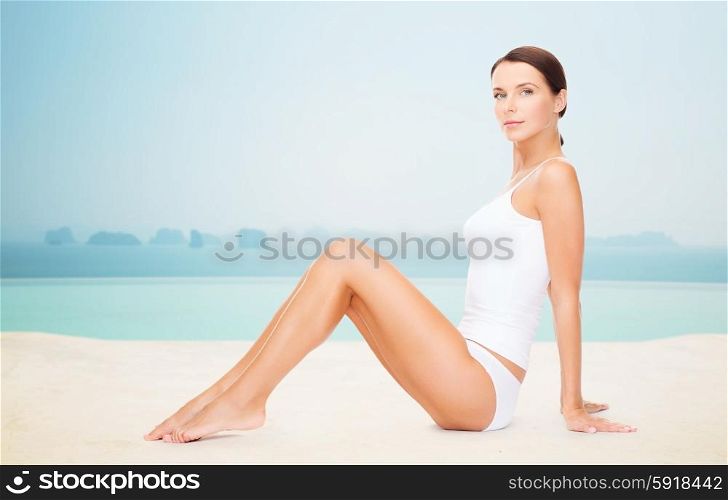 people, beauty, spa and resort concept - beautiful woman in cotton underwear over infinity edge pool background
