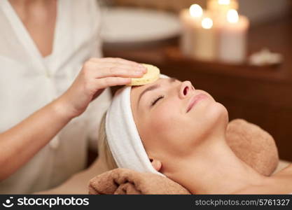 people, beauty, spa, cosmetology and relaxation concept - close up of beautiful young woman lying with closed eyes having face cleaning by sponge in spa
