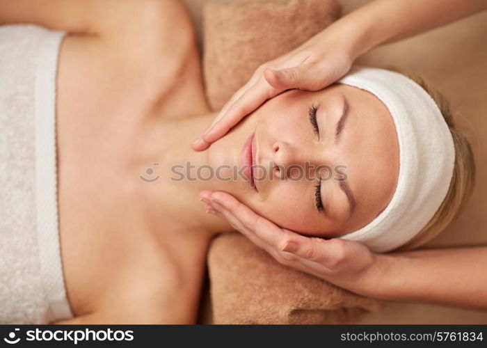 people, beauty, spa, cosmetology and relaxation concept - close up of beautiful young woman lying with closed eyes having face massage in spa