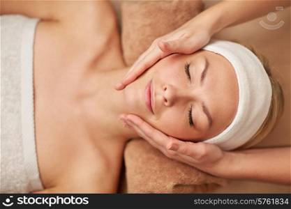 people, beauty, spa, cosmetology and relaxation concept - close up of beautiful young woman lying with closed eyes having face massage in spa