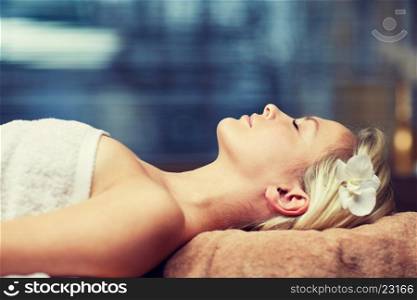 people, beauty, spa, healthy lifestyle and relaxation concept - beautiful young woman lying with closed eyes in spa