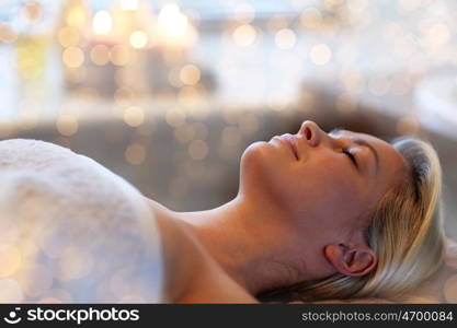 people, beauty, spa, healthy lifestyle and relaxation concept - beautiful young woman lying with closed eyes in spa