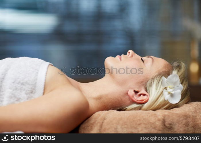 people, beauty, spa, healthy lifestyle and relaxation concept - beautiful young woman lying with closed eyes in spa