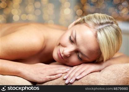people, beauty, spa, healthy lifestyle and relaxation concept - close up of beautiful young woman lying on massage table in spa