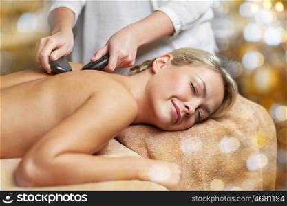 people, beauty, spa, healthy lifestyle and relaxation concept - close up of beautiful young woman having hot stone massage in spa