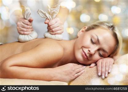 people, beauty, spa, healthy lifestyle and relaxation concept - close up of beautiful young woman lying and having herbal bag massage in spa