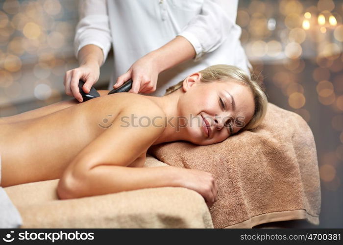 people, beauty, spa, healthy lifestyle and relaxation concept - close up of beautiful young woman having hot stone massage in spa