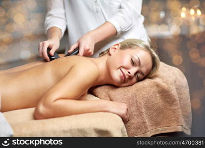 people, beauty, spa, healthy lifestyle and relaxation concept - close up of beautiful young woman having hot stone massage in spa