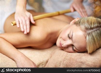 people, beauty, spa, healthy lifestyle and relaxation concept - close up of beautiful young woman lying with closed eyes and having bamboo massage in spa