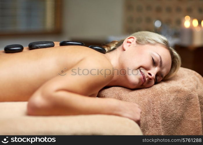 people, beauty, spa, healthy lifestyle and relaxation concept - close up of beautiful young woman having hot stone massage in spa