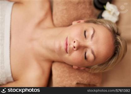 people, beauty, spa, healthy lifestyle and relaxation concept - close up of beautiful smiling young woman lying with closed eyes in spa