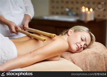 people, beauty, spa, healthy lifestyle and relaxation concept - close up of beautiful young woman lying with closed eyes and having bamboo massage in spa