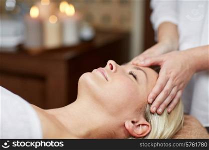 people, beauty, spa, healthy lifestyle and relaxation concept - close up of beautiful young woman lying with closed eyes and having face or head massage in spa