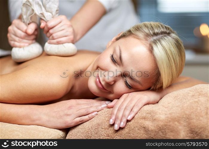 people, beauty, spa, healthy lifestyle and relaxation concept - close up of beautiful young woman lying and having herbal bag massage in spa