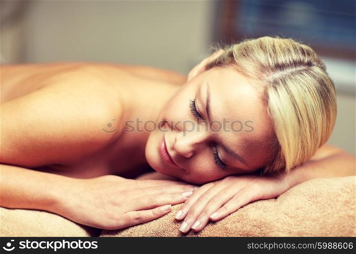 people, beauty, spa, healthy lifestyle and relaxation concept - close up of beautiful young woman lying on massage table in spa