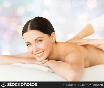 people, beauty, spa, holidays and body care concept - happy beautiful woman having back massage over blue lights background