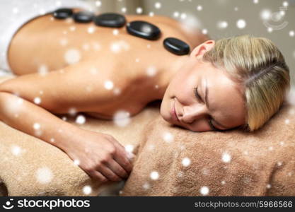 people, beauty, spa, winter and relaxation concept - close up of beautiful young woman having hot stone back massage in spa salon with snow effect