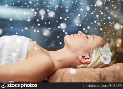people, beauty, spa, winter and relaxation concept - close up of beautiful smiling young woman lying with closed eyes in spa salon with snow effect