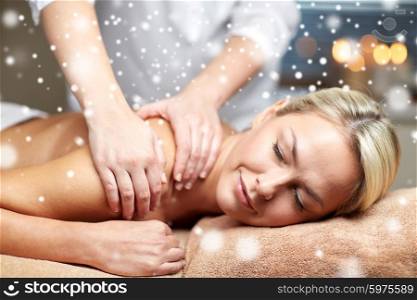 people, beauty, spa, winter and relaxation concept - close up of beautiful young woman lying with closed eyes and having hand back massage in spa salon with snow effect