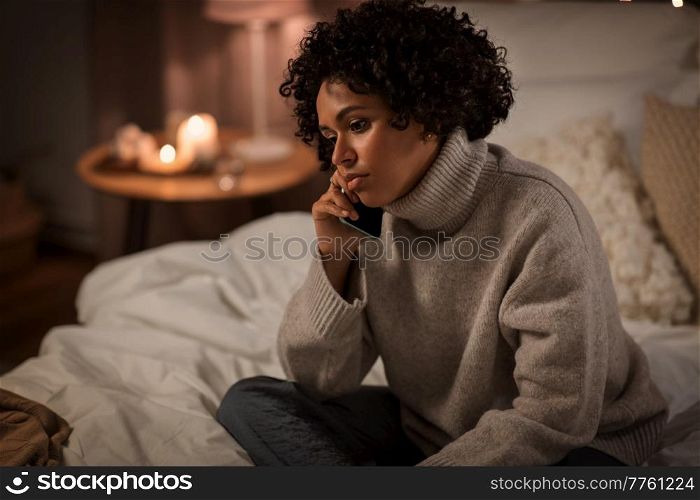 people, bedtime and communication concept - woman calling on smartphone sitting in bed at home. woman calling on smartphone in bed at home