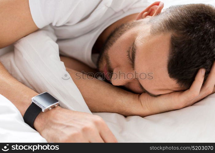 people, bedtime and rest concept - close up of man with smartwatch sleeping in bed. close up of man with smartwatch sleeping in bed