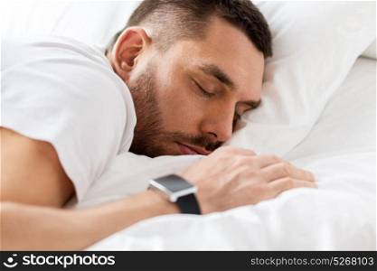 people, bedtime and rest concept - close up of man with smartwatch sleeping in bed. close up of man with smartwatch sleeping in bed