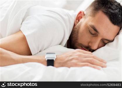 people, bedtime and rest concept - close up of man with smartwatch sleeping in bed. close up of man with smartwatch sleeping in bed