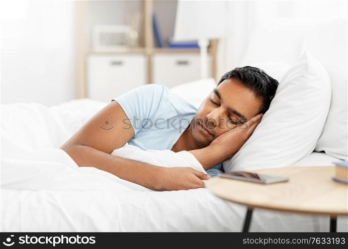 people, bedtime and rest concept - indian man sleeping in bed at home. indian man sleeping in bed at home
