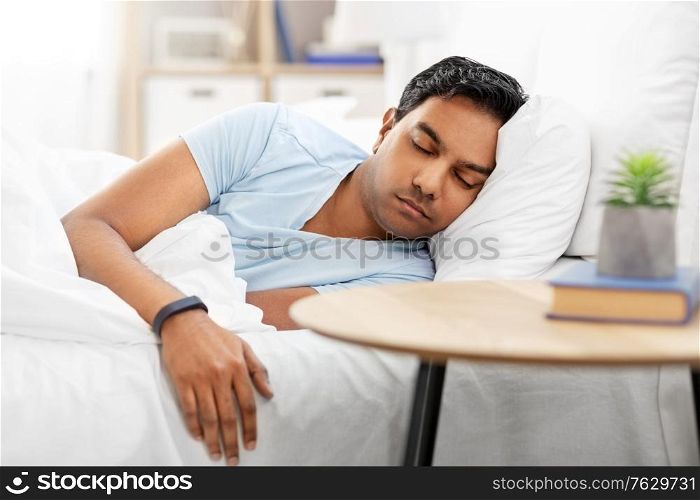 people, bedtime and rest concept - indian man with health tracker sleeping in bed at home. indian man with tracker sleeping in bed at home