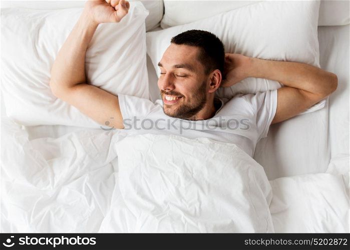 people, bedtime and rest concept - man lying in bed at home. man lying in bed at home