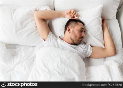 people, bedtime and rest concept - man sleeping in bed at home. man sleeping in bed at home
