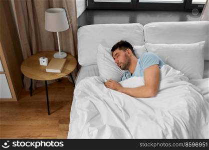 people, bedtime and rest concept - man sleeping in bed at home. man sleeping in bed at home