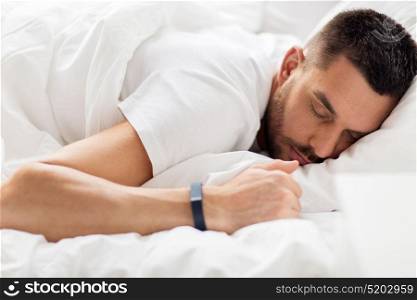 people, bedtime and rest concept - man with smartwatch sleeping in bed. man with smartwatch sleeping in bed