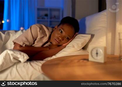 people, bedtime and rest concept - sleepless african american woman lying in bed at night. sleepless african woman lying in bed at night