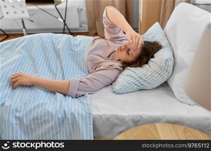 people, bedtime and rest concept - sleepy teenage girl lying in bed at home in morning. sleepy girl lying in bed at home in morning