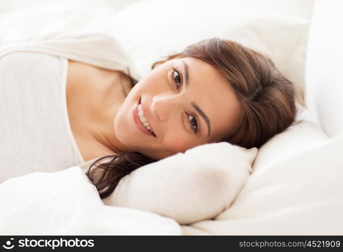 people, bedtime and rest concept - smiling young woman lying in bed at home