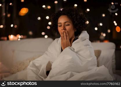 people, bedtime and rest concept - tired sleepy woman wrapped in blanket yawning sitting in bed at night. yawning woman wrapped in blanket in bed at night