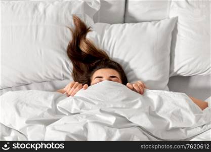 people, bedtime and rest concept - woman lying in bed under white blanket or duvet. woman lying in bed under white blanket or duvet