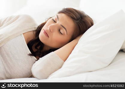 people, bedtime and rest concept - young woman sleeping in bed at home