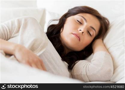 people, bedtime and rest concept - young woman sleeping in bed at home