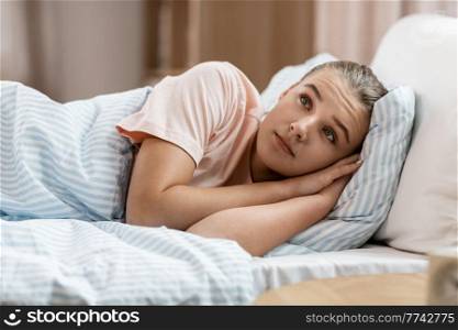 people, bedtime and sleeping concept - awake girl lying in bed at home. awake girl lying in bed at home