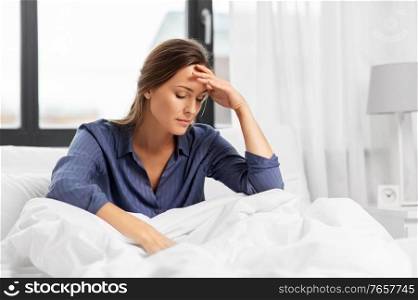 people, bedtime and sleeping concept - sleepy woman sitting in bed at home. sleepy woman sitting in bed at home