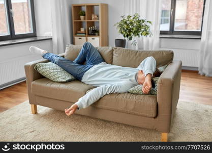 people, boredom and depression concept - bored or lazy young man lying on sofa at home. bored or lazy young man lying on sofa at home
