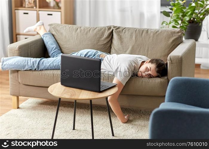 people, boredom and depression concept - bored or lazy young woman with laptop computer lying on sofa at home. bored woman with laptop lying on sofa at home