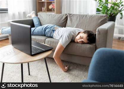 people, boredom and depression concept - bored or lazy young woman with laptop computer lying on sofa at home. bored woman with laptop lying on sofa at home