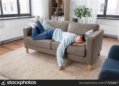 people, boredom and depression concept - lazy young man sleeping on sofa at home. young man sleeping on sofa at home